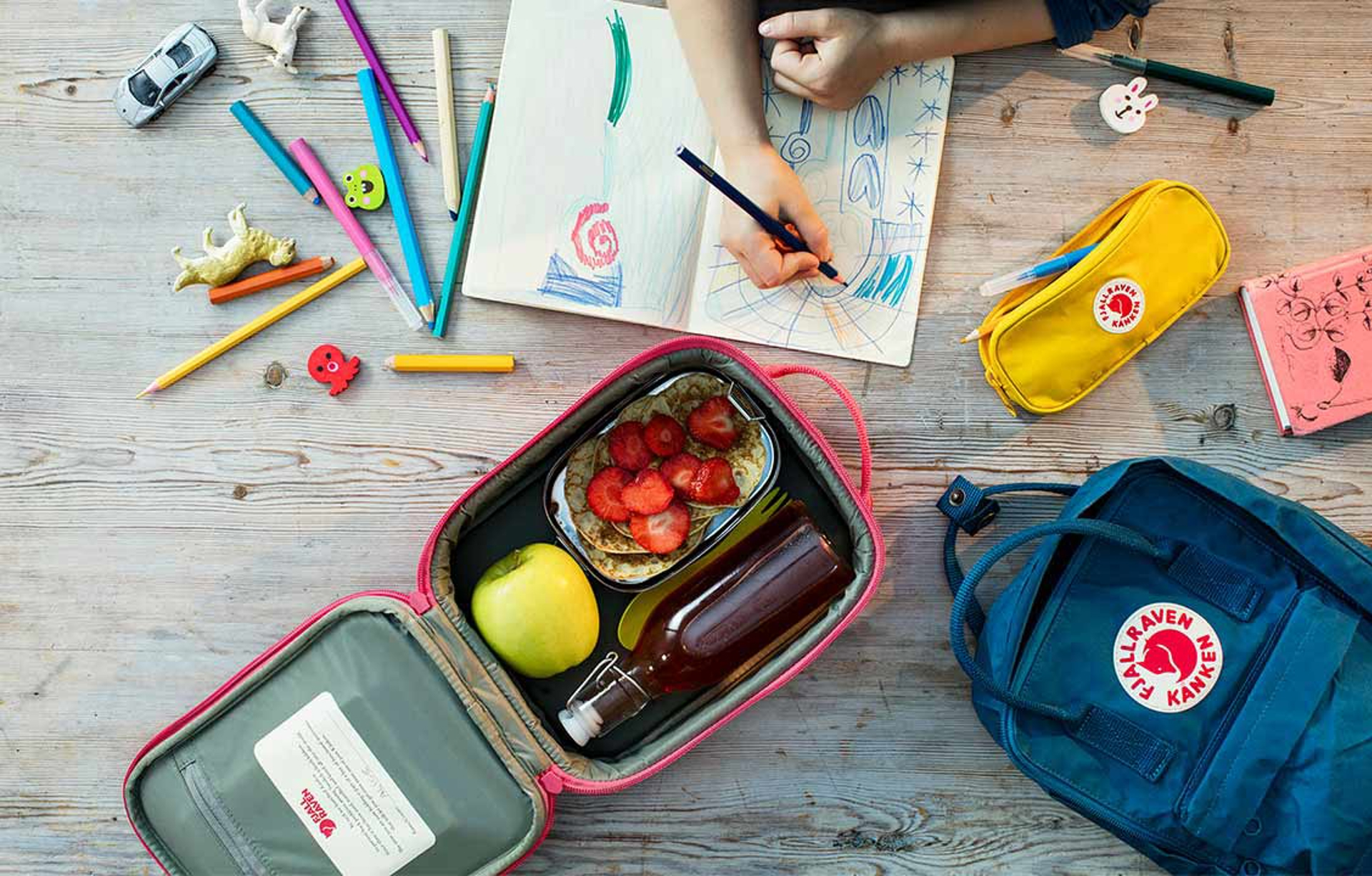 a child with fjallraven bag, lunch bag, and coloring supplies